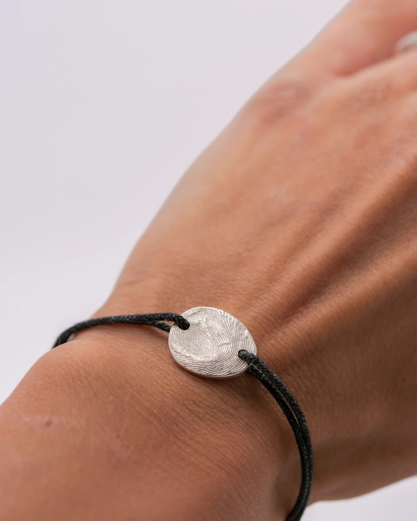 Bracelet sur cordon argent avec empreinte digitale porté.
