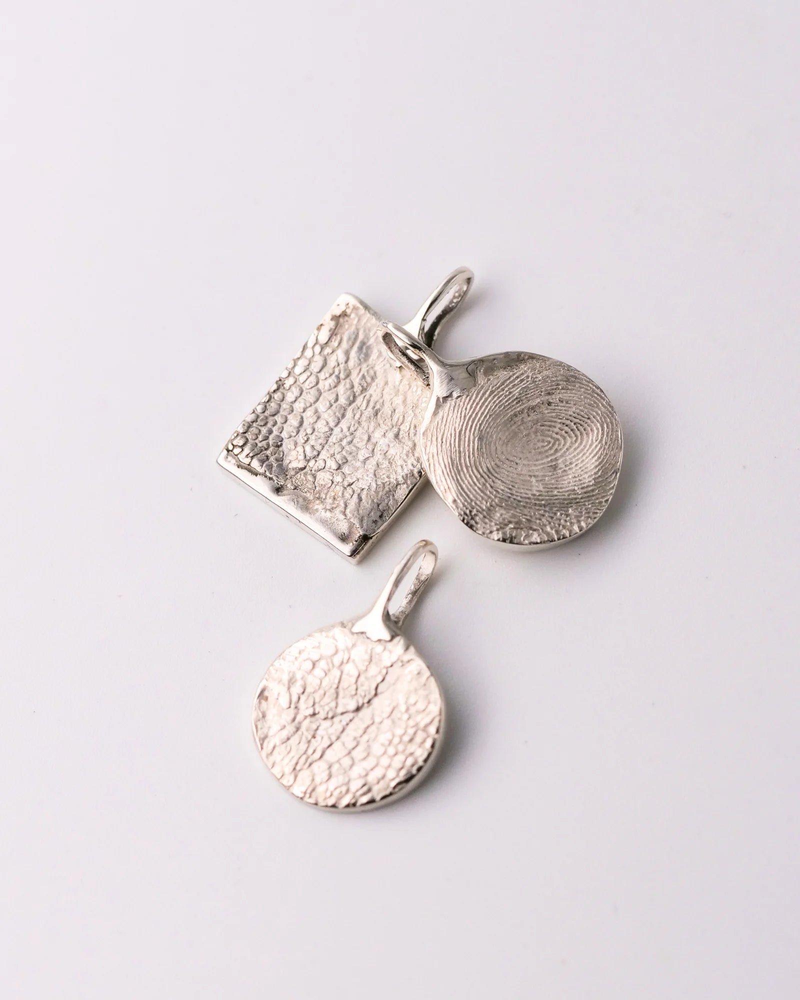 Trio de pendentifs en argent avec empreinte animale.