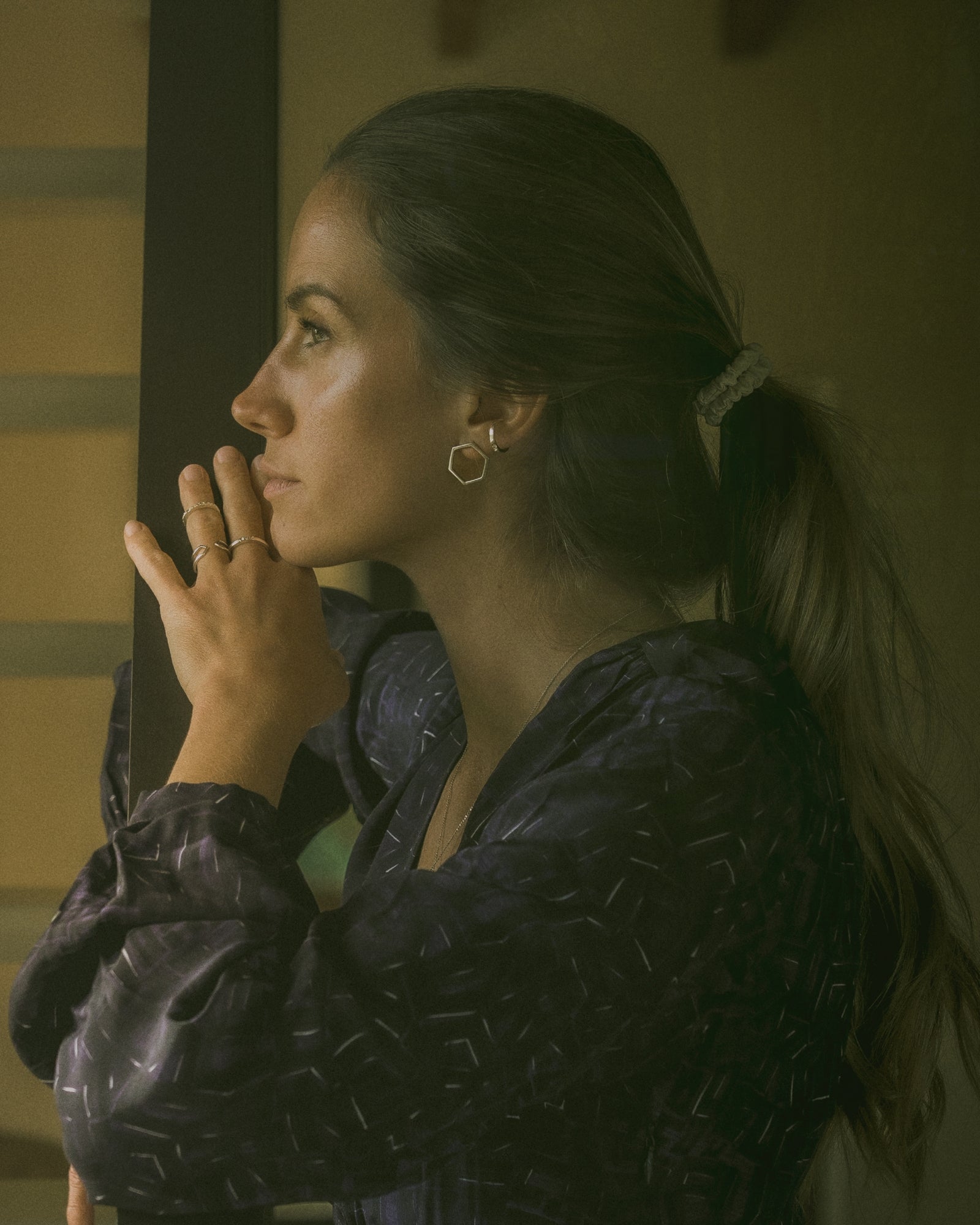 Photo portée d'une accumulation de bijoux en argent ou or blanc éthique avec une blouse de la marque Soi Paris