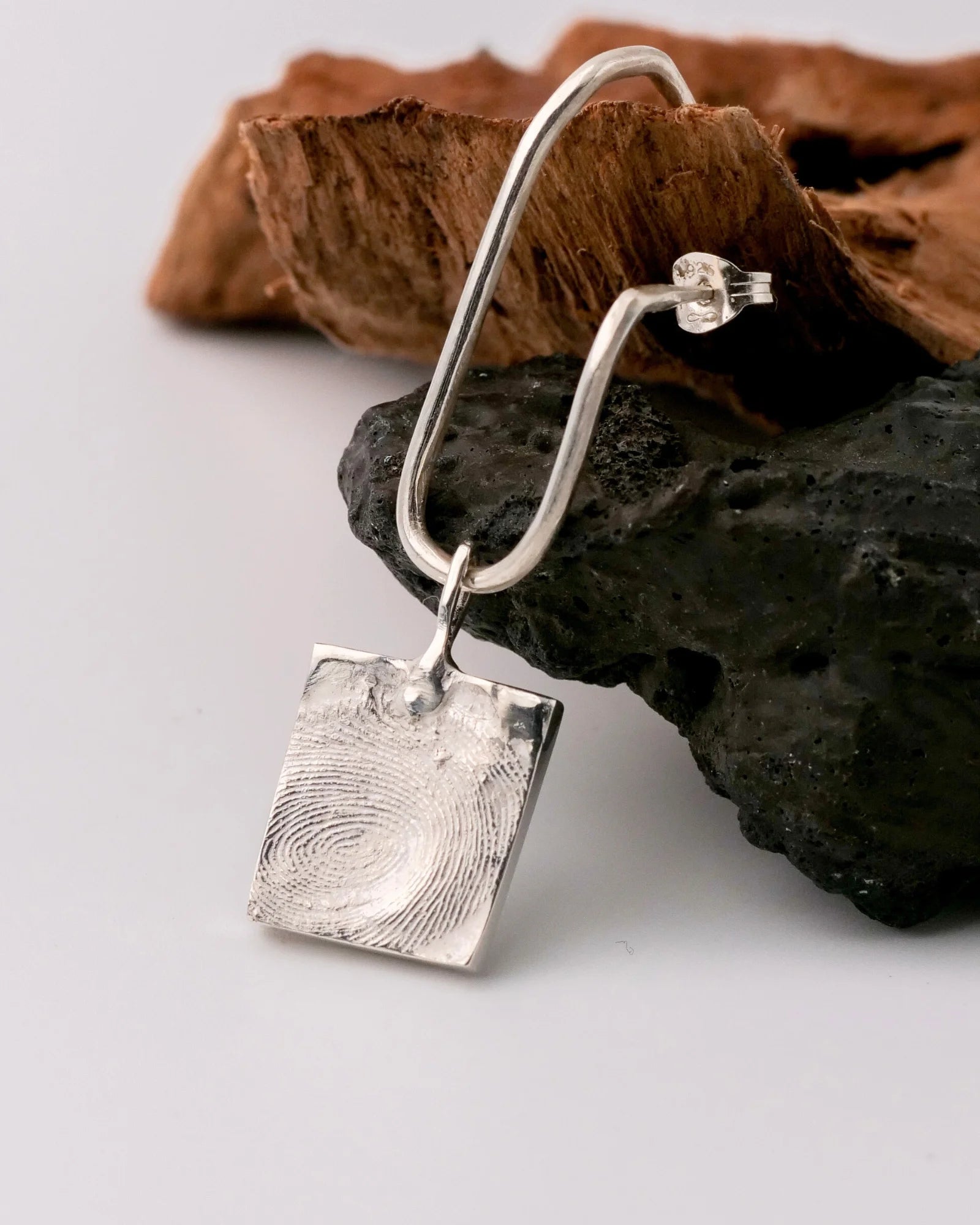 Pendentif carrée en argent avec empreinte digitale sur boucle d'oreille.