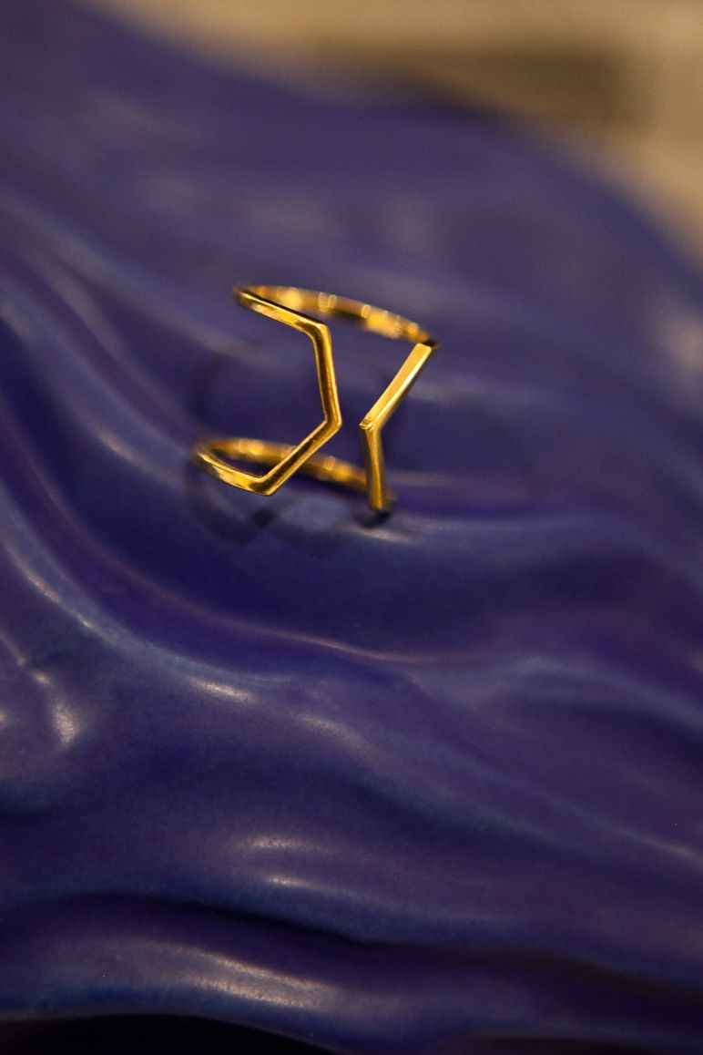Photo du modèle de bague éthique Dualité large en or jaune fairmined non portée sur fond céramique vagues bleues