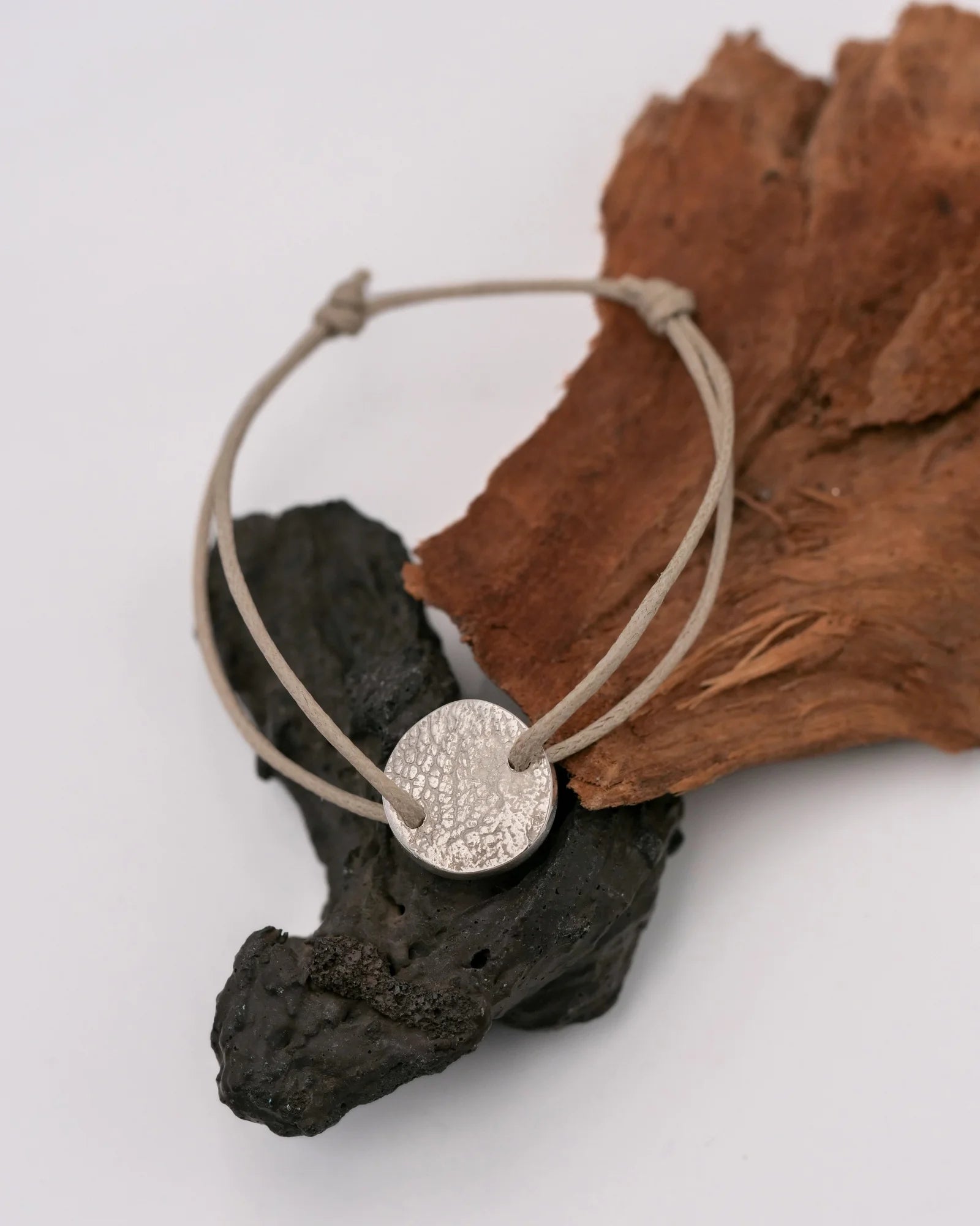 Bracelet cordon avec médaille ronde en argent avec empreinte animale.