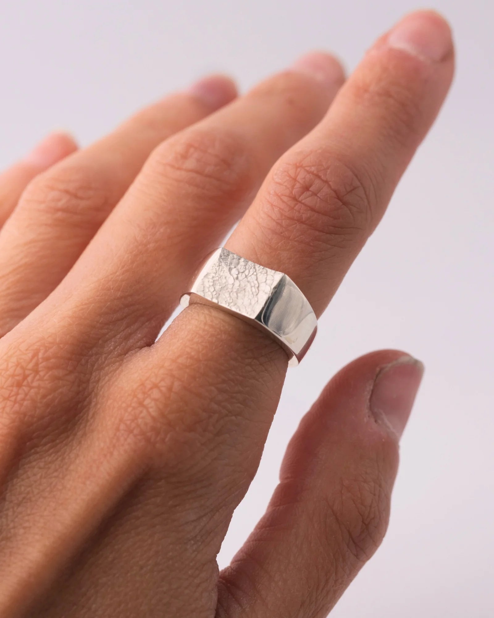 Chevalière large en argent avec empreinte animale portée.