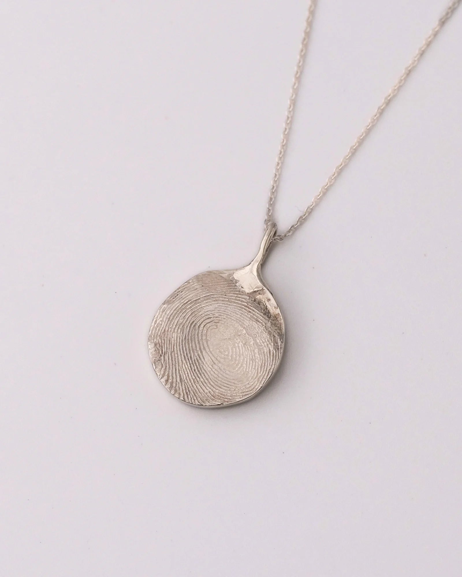 Collier avec pendentif rond en argent avec empreinte digitale.