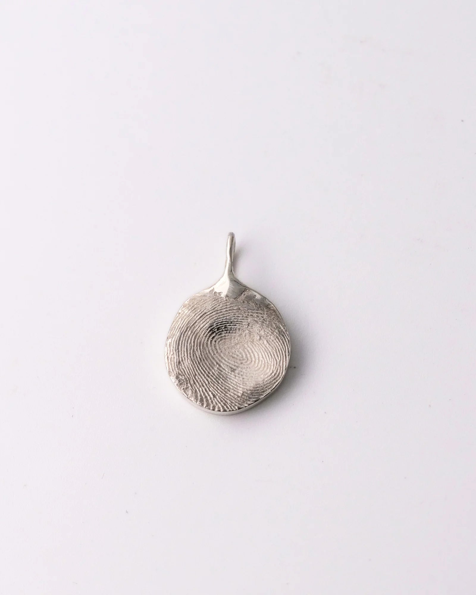 Pendentif rond en argent avec empreinte digitale.
