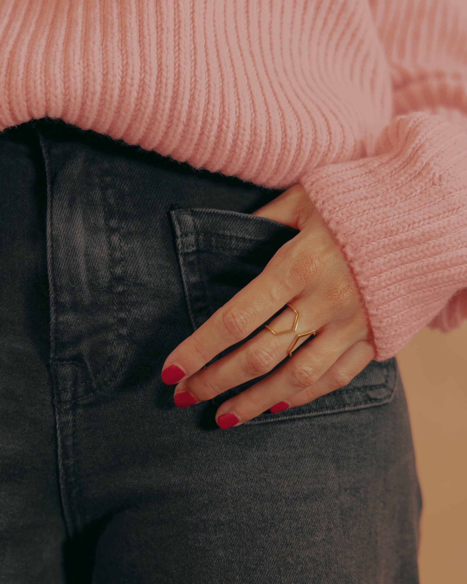 Photo du modèle de bague éthique Dualité large en vermeil portée à la main, fond jean noir et pull rose