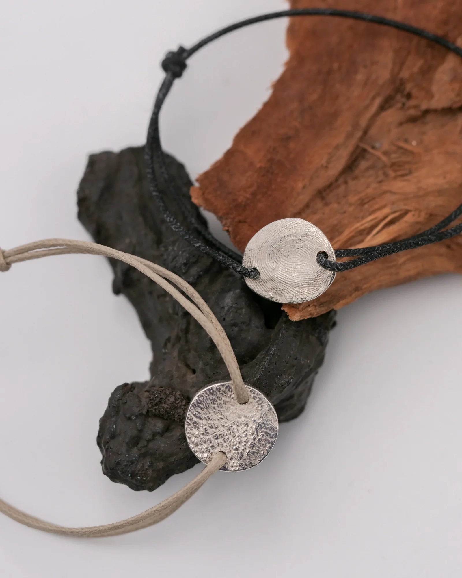 Duo de bracelets avec empreinte digitale et animale sur cordon noir et sable.