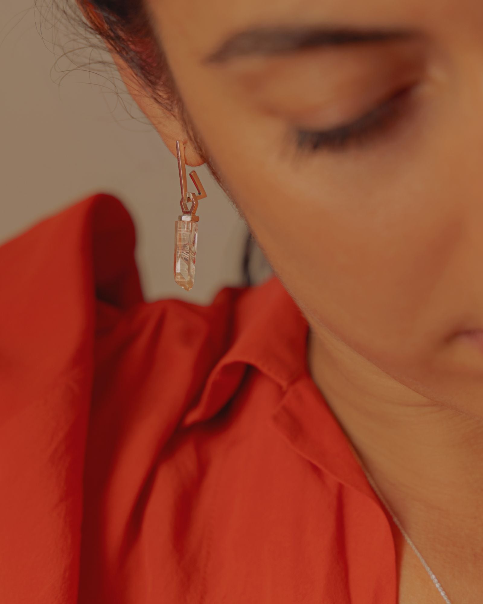 Photo portée d'une boucle d'oreille éthique modèle mouvement en argent labellisé, porté avec un pendentif éthique modèle Infirme en argent labellisé et quartz de France.
